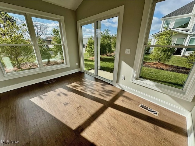 doorway to outside featuring dark wood-style floors, visible vents, vaulted ceiling, and baseboards