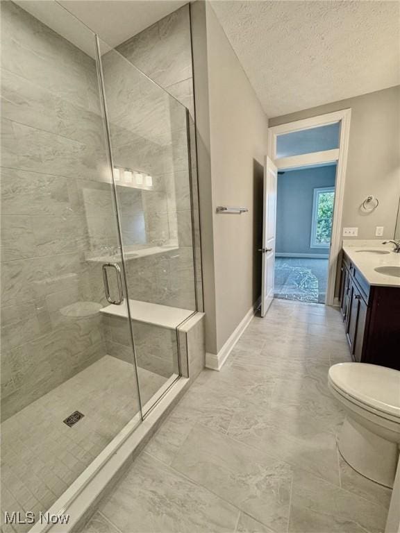 bathroom featuring toilet, a textured ceiling, a shower stall, vanity, and baseboards