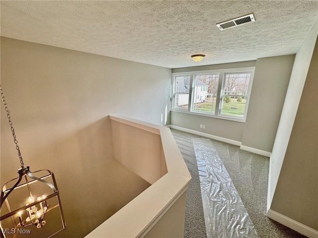 hall featuring carpet, an upstairs landing, visible vents, and baseboards