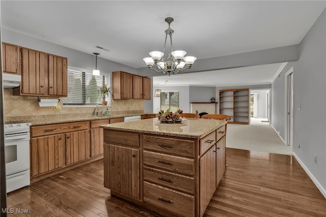 kitchen with white appliances, a kitchen island, dark wood finished floors, under cabinet range hood, and tasteful backsplash