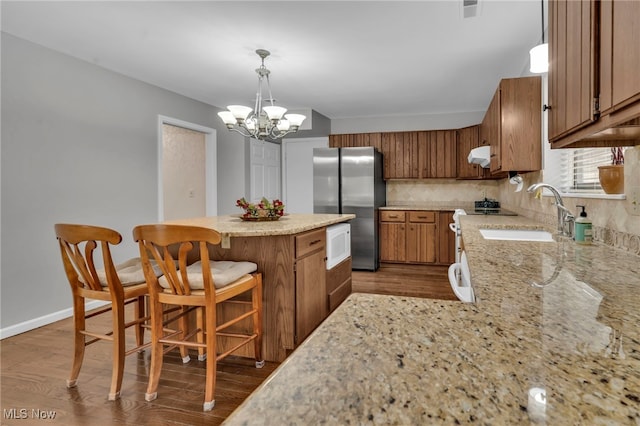 kitchen featuring a sink, brown cabinets, dark wood finished floors, and freestanding refrigerator