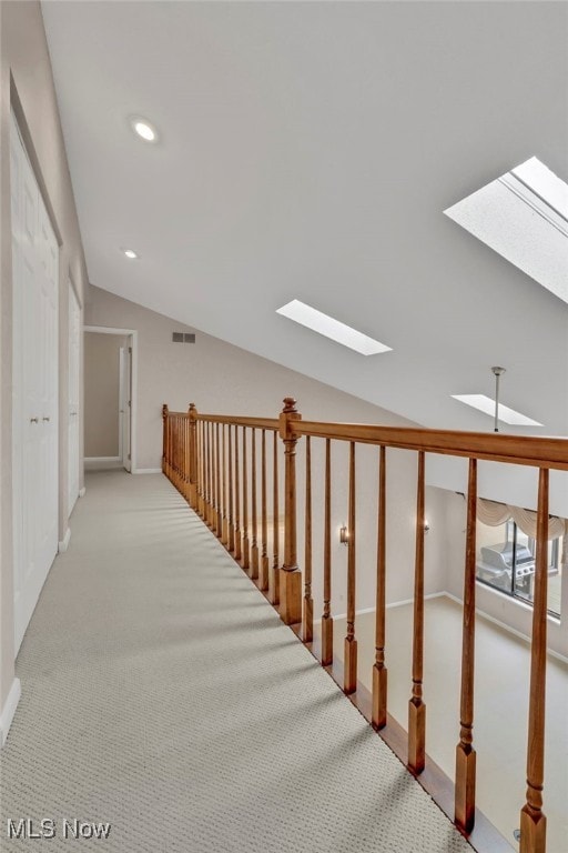 hall with lofted ceiling with skylight, visible vents, recessed lighting, and carpet floors