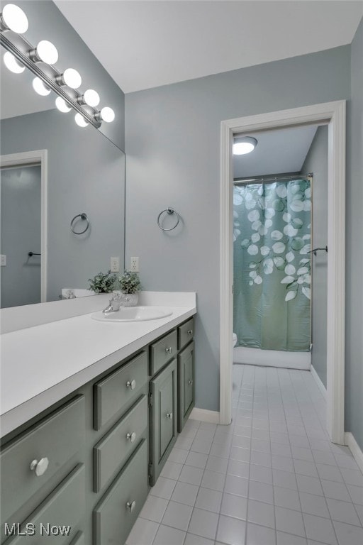 bathroom with vanity, curtained shower, toilet, and baseboards