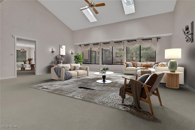 carpeted living room featuring baseboards, high vaulted ceiling, a skylight, and a ceiling fan