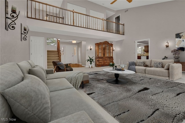 living room featuring a high ceiling, stairs, and ceiling fan