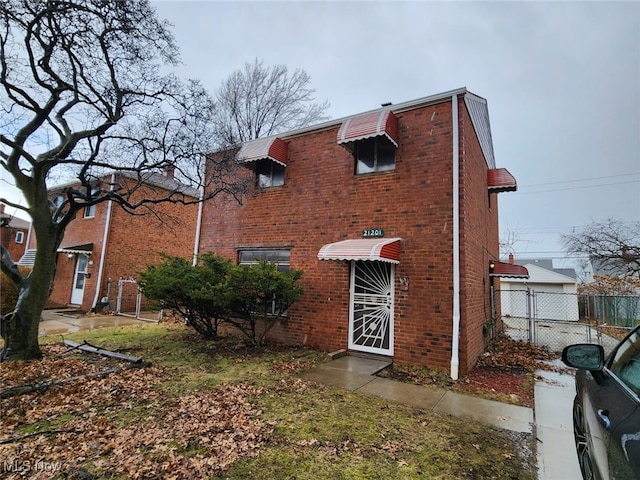 view of front facade featuring brick siding and fence