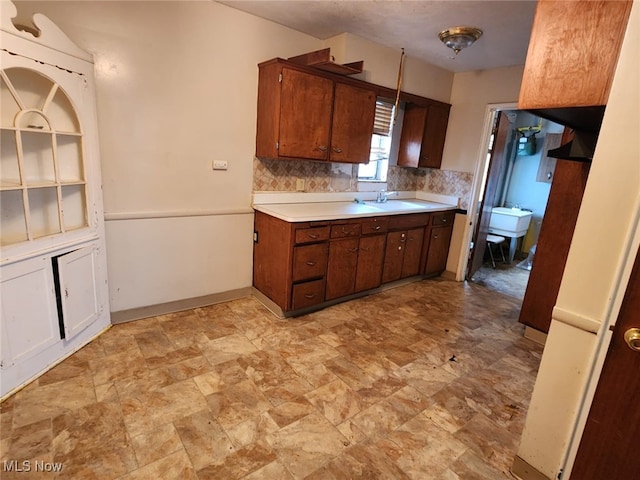 kitchen featuring brown cabinetry, tasteful backsplash, light countertops, and a sink