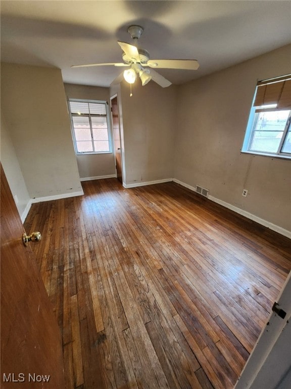 spare room with visible vents, ceiling fan, baseboards, and hardwood / wood-style flooring