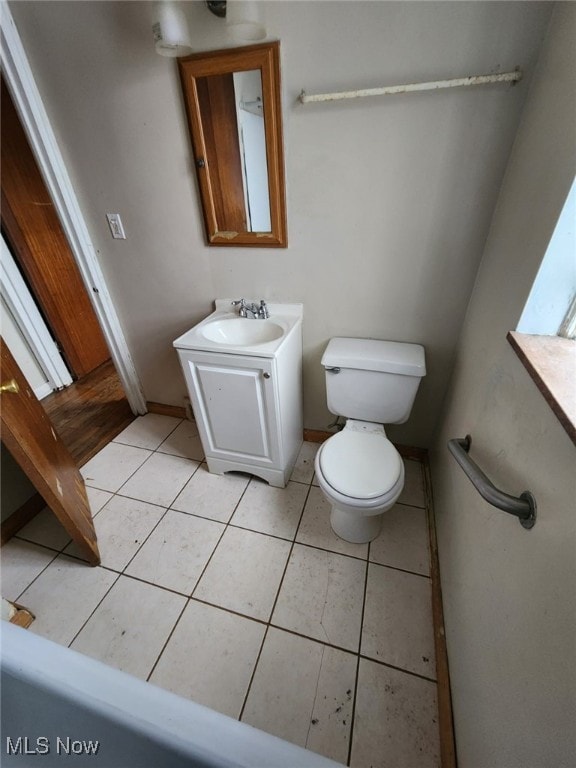 half bath featuring vanity, tile patterned flooring, toilet, and baseboards