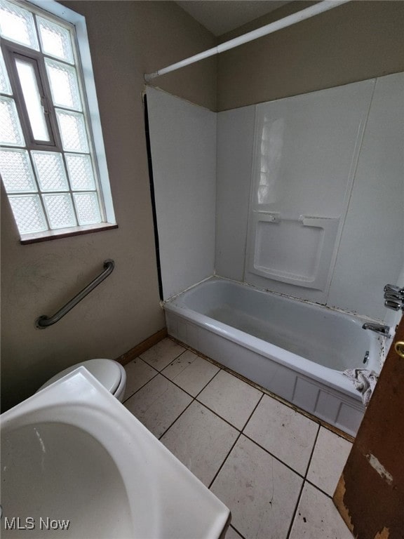 full bath featuring tub / shower combination, tile patterned flooring, toilet, and baseboards