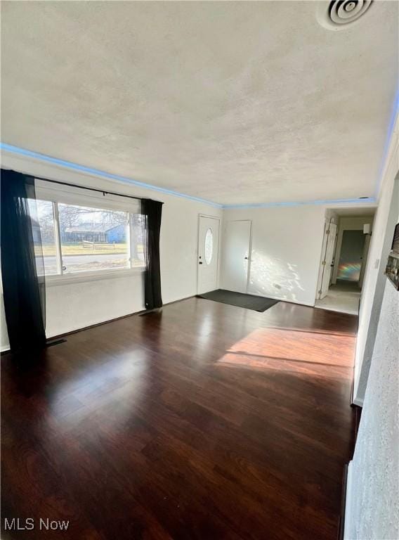 unfurnished living room with a textured ceiling and wood finished floors