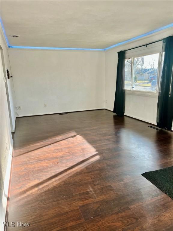 spare room with ornamental molding, wood finished floors, and visible vents