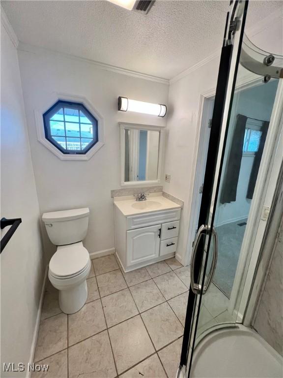 bathroom with toilet, vanity, tile patterned flooring, crown molding, and a textured ceiling