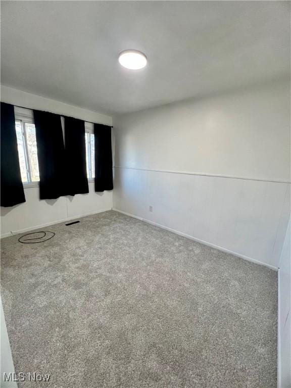 empty room featuring carpet, visible vents, and baseboards