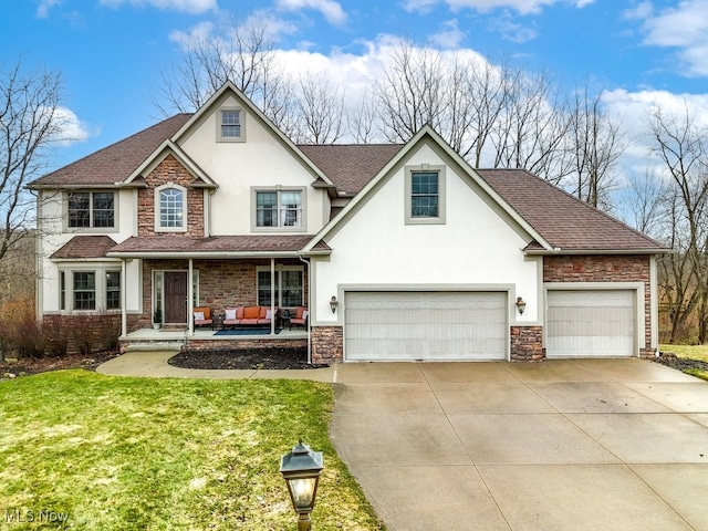 traditional-style home with a porch, concrete driveway, stone siding, stucco siding, and a front lawn