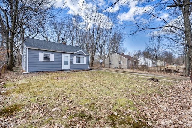 bungalow featuring roof with shingles, a chimney, fence, and a front yard