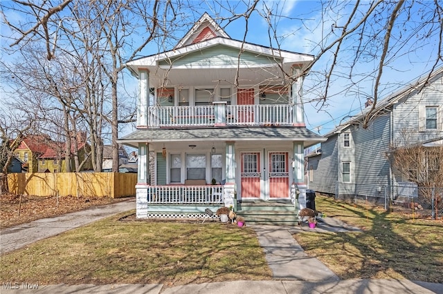 view of front of house featuring covered porch, fence, a balcony, and a front lawn