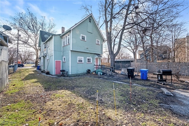 back of property featuring a chimney and fence