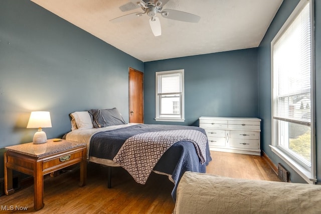 bedroom featuring wood finished floors, visible vents, and a ceiling fan