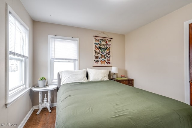 bedroom featuring multiple windows, baseboards, and wood finished floors