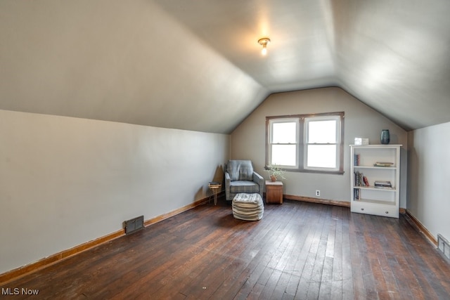 unfurnished room with lofted ceiling, dark wood-type flooring, visible vents, and baseboards