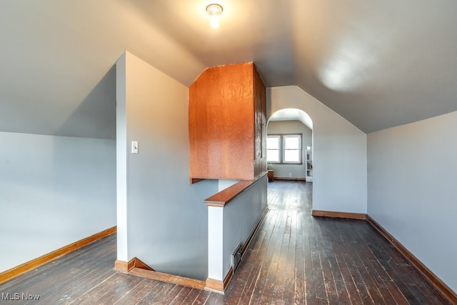 bonus room with vaulted ceiling, wood-type flooring, arched walkways, and baseboards