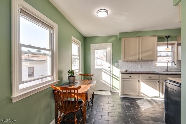 kitchen featuring dark countertops, a sink, range, and decorative backsplash