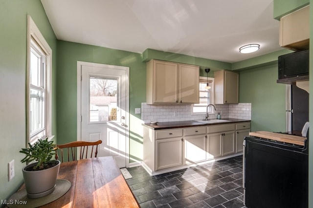 kitchen with decorative backsplash, stone finish flooring, black range with electric stovetop, and a sink