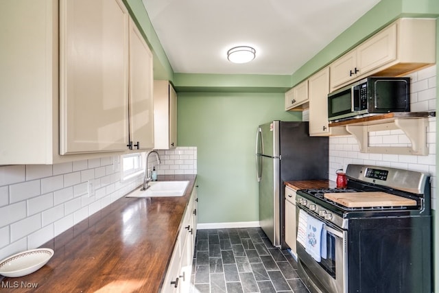 kitchen with baseboards, butcher block counters, appliances with stainless steel finishes, and a sink