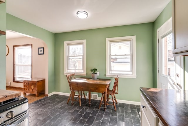 dining room featuring arched walkways and baseboards