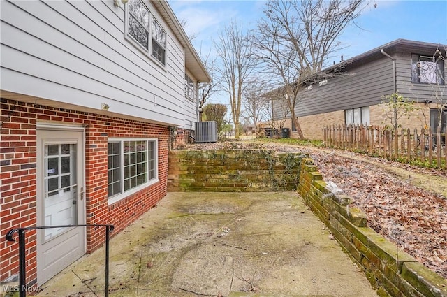 exterior space with cooling unit, a patio area, brick siding, and fence