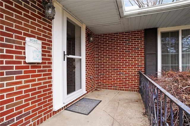 view of exterior entry with a porch and brick siding