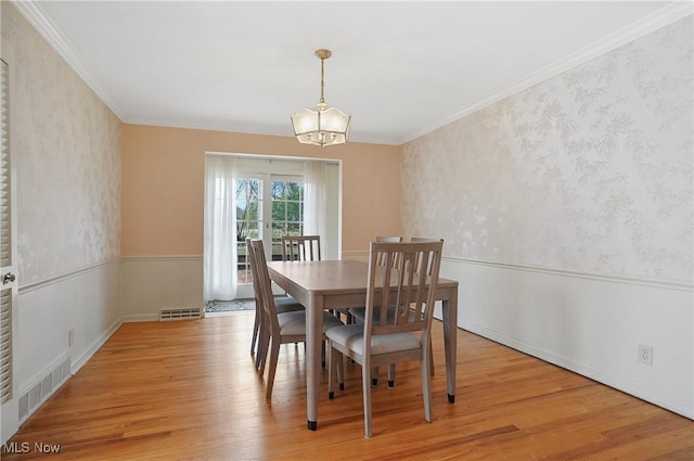 dining area featuring light wood-style floors, visible vents, and wallpapered walls