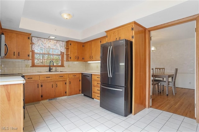 kitchen featuring light countertops, backsplash, freestanding refrigerator, a sink, and dishwasher