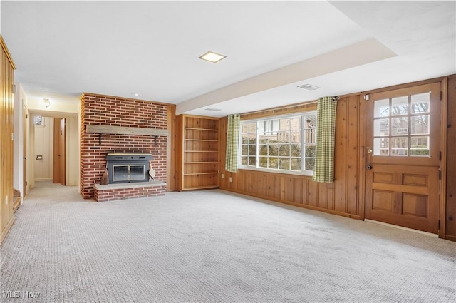 unfurnished living room featuring carpet floors, a fireplace, built in features, and wooden walls