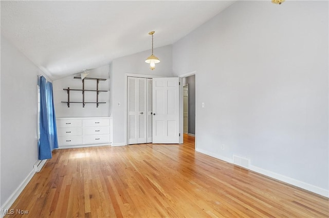 unfurnished bedroom with light wood-style flooring, visible vents, baseboards, vaulted ceiling, and a closet