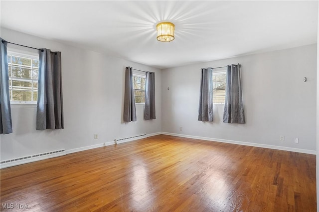 spare room with hardwood / wood-style flooring, a baseboard radiator, and a wealth of natural light