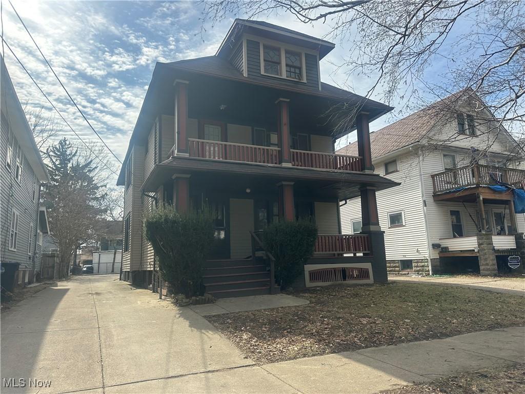 traditional style home featuring driveway, a porch, and a balcony