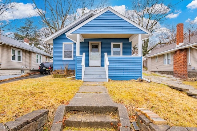 bungalow-style home with covered porch and a front lawn