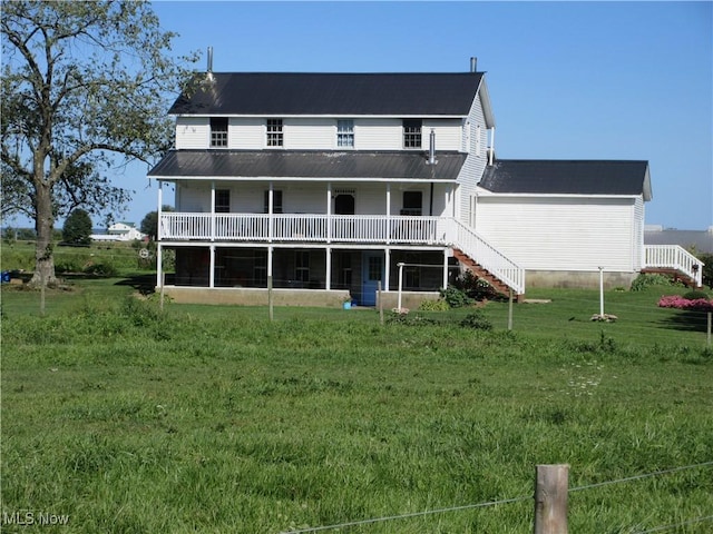 rear view of property featuring metal roof, a lawn, and stairway