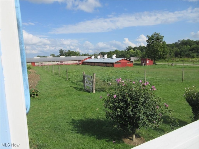 view of yard with an outbuilding, a rural view, an outdoor structure, and fence