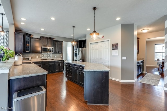 kitchen with backsplash, dark wood-style flooring, stainless steel appliances, and light countertops