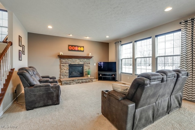 carpeted living area with baseboards, stairs, a textured ceiling, a fireplace, and recessed lighting