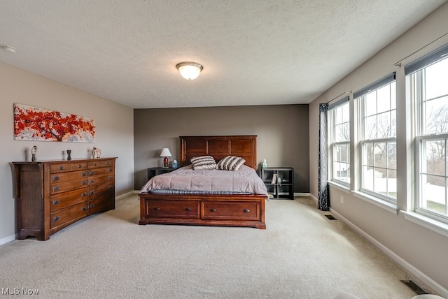 bedroom with visible vents, light colored carpet, a textured ceiling, and baseboards