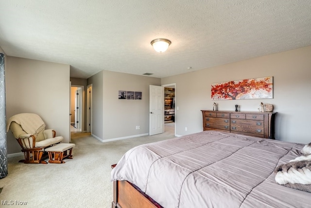 bedroom featuring visible vents, light colored carpet, a textured ceiling, and baseboards