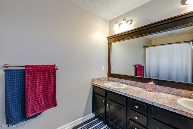 full bath featuring double vanity, a textured ceiling, and a sink