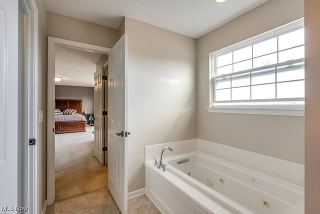 full bathroom with a textured ceiling, a tub with jets, baseboards, and ensuite bathroom