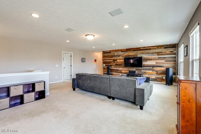 living area with light carpet, an accent wall, a textured ceiling, wood walls, and recessed lighting