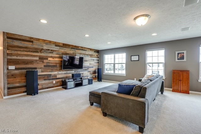 living room featuring light carpet, wood walls, a textured ceiling, and recessed lighting