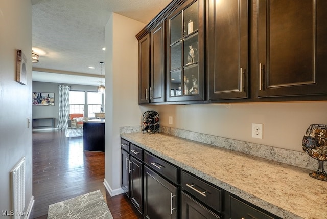 kitchen featuring dark wood-style floors, light countertops, visible vents, glass insert cabinets, and dark brown cabinets